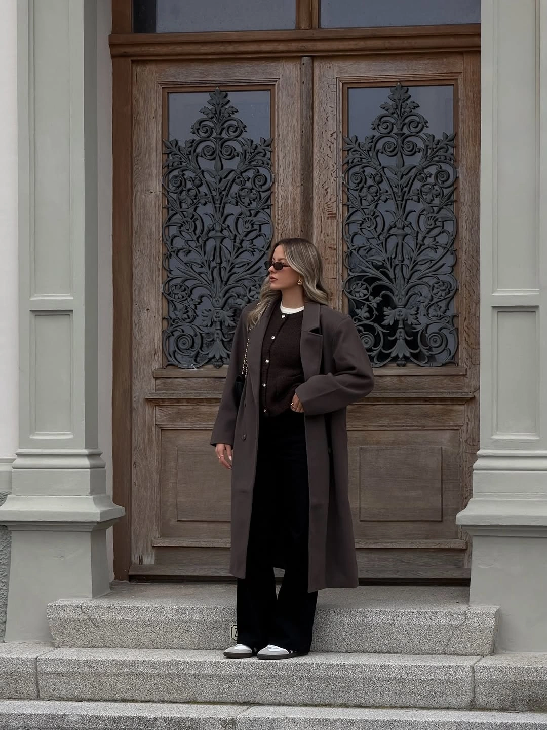 Long dark coat over black outfit with white shoes