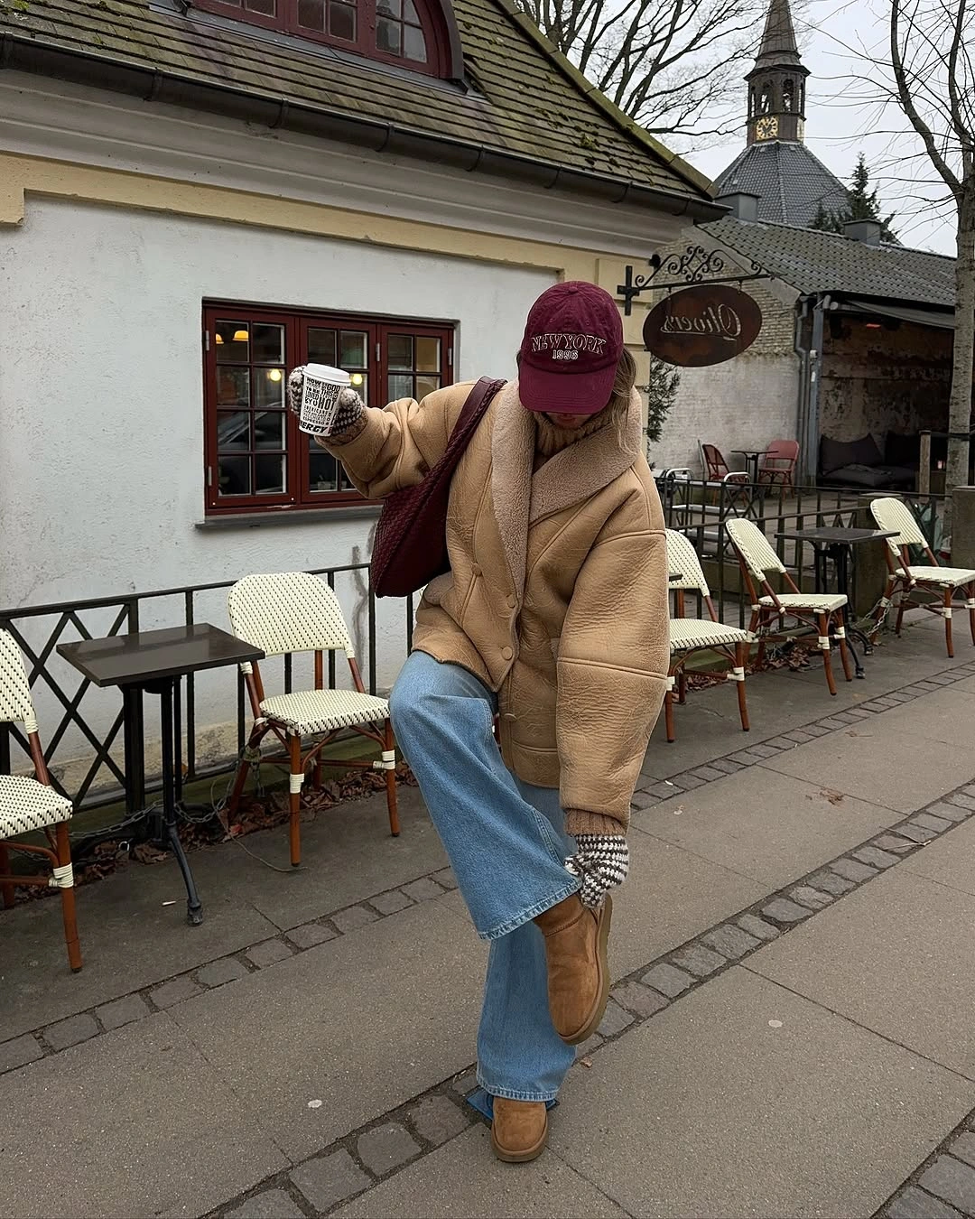 Tan shearling-look coat with jeans, burgundy cap and tan shoes