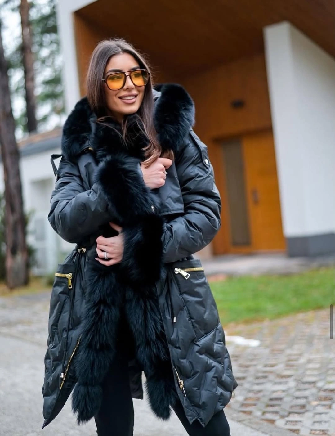 Glossy black puffer with fuzzy hood and amber sunglasses