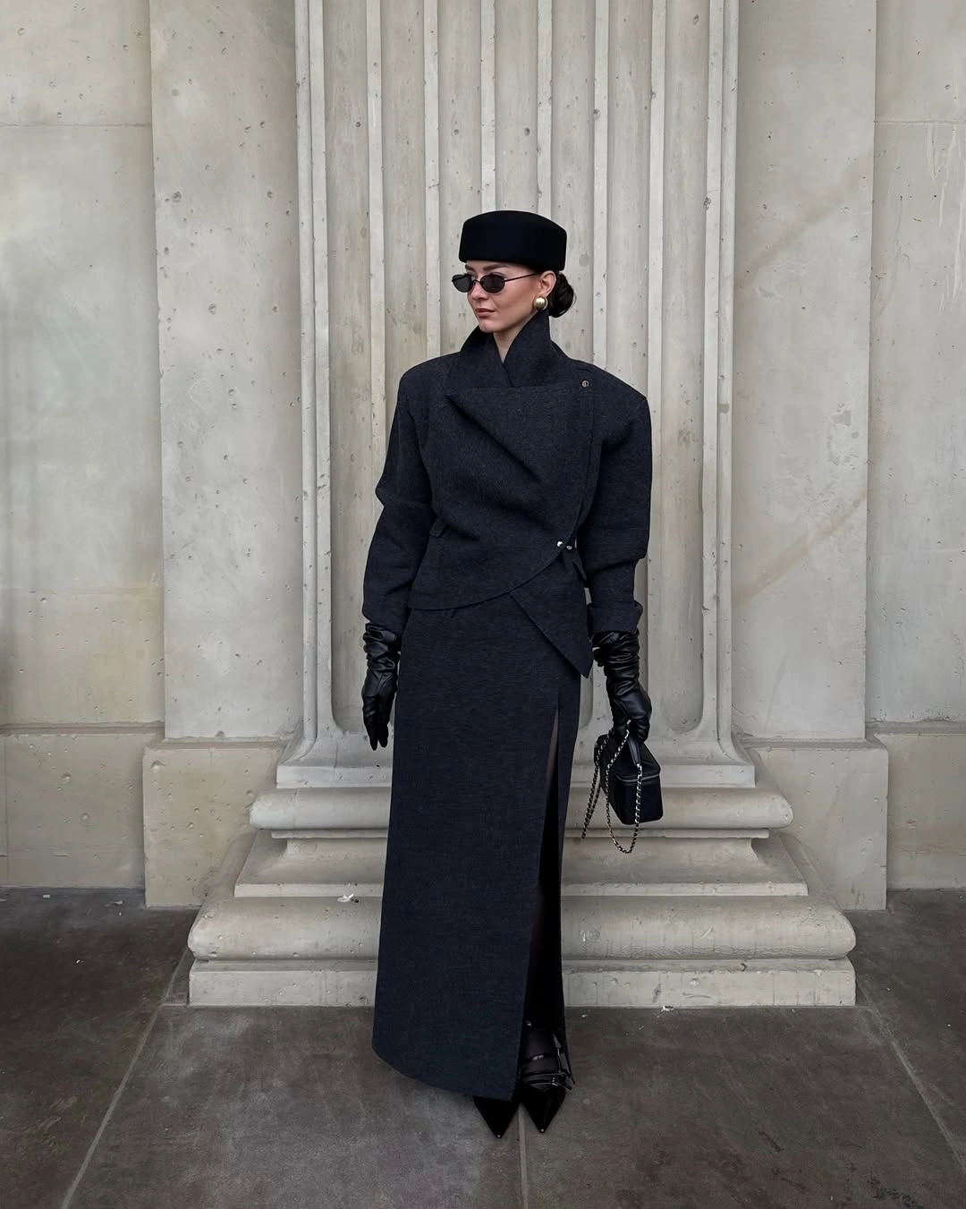 Long black belted coat with black hat, gloves, boots, and handbag