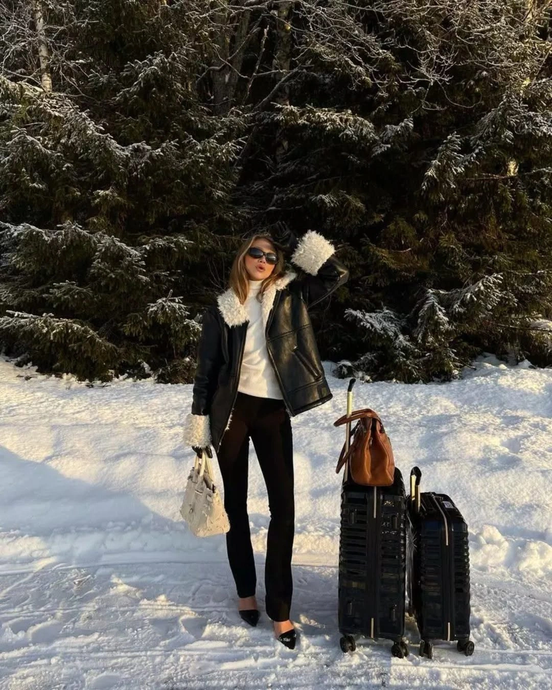 Black short jacket and trousers with cream scarf, white handbag, and pointed black shoes