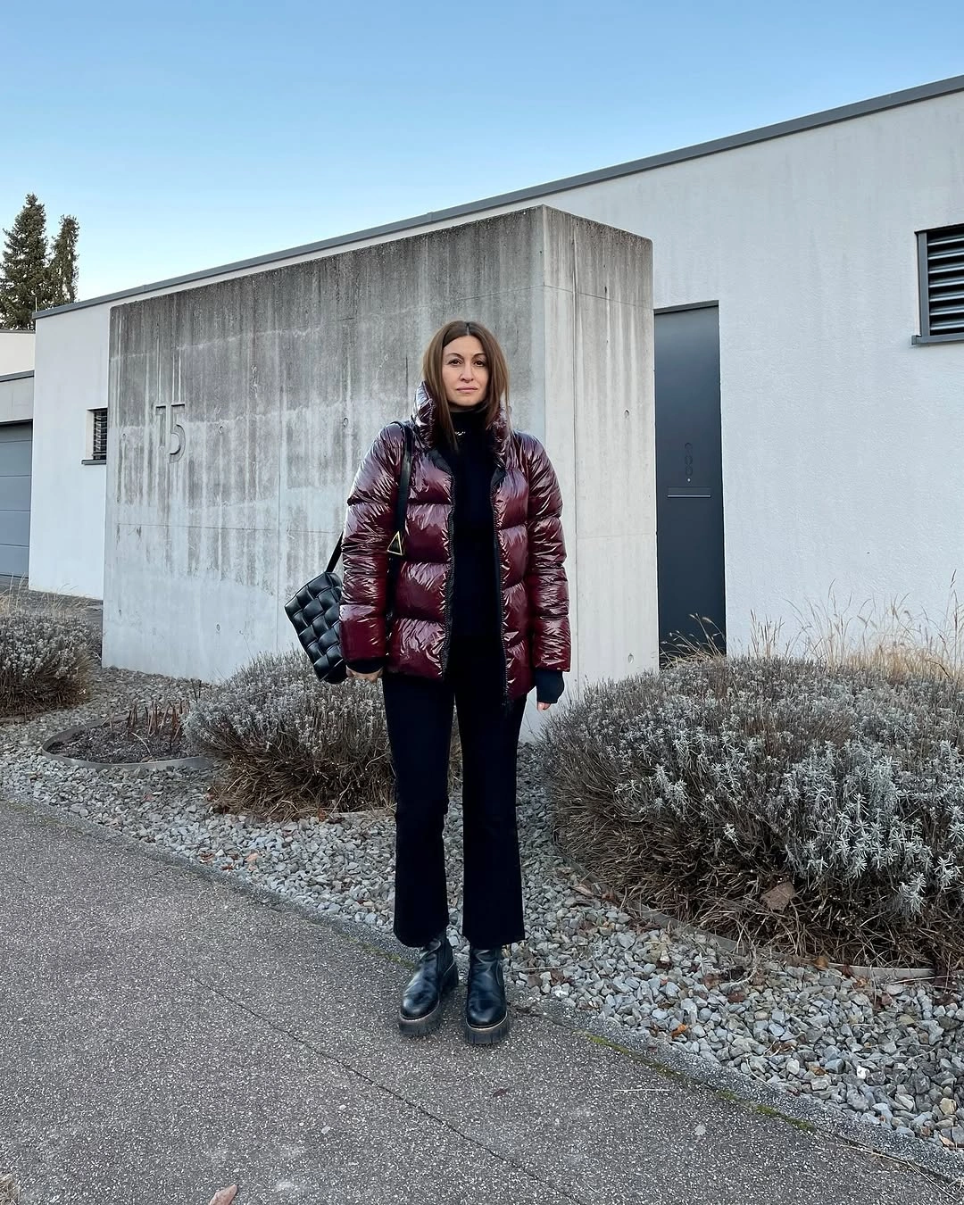 Glossy burgundy puffer-style jacket with dark trousers, black boots, and scarf