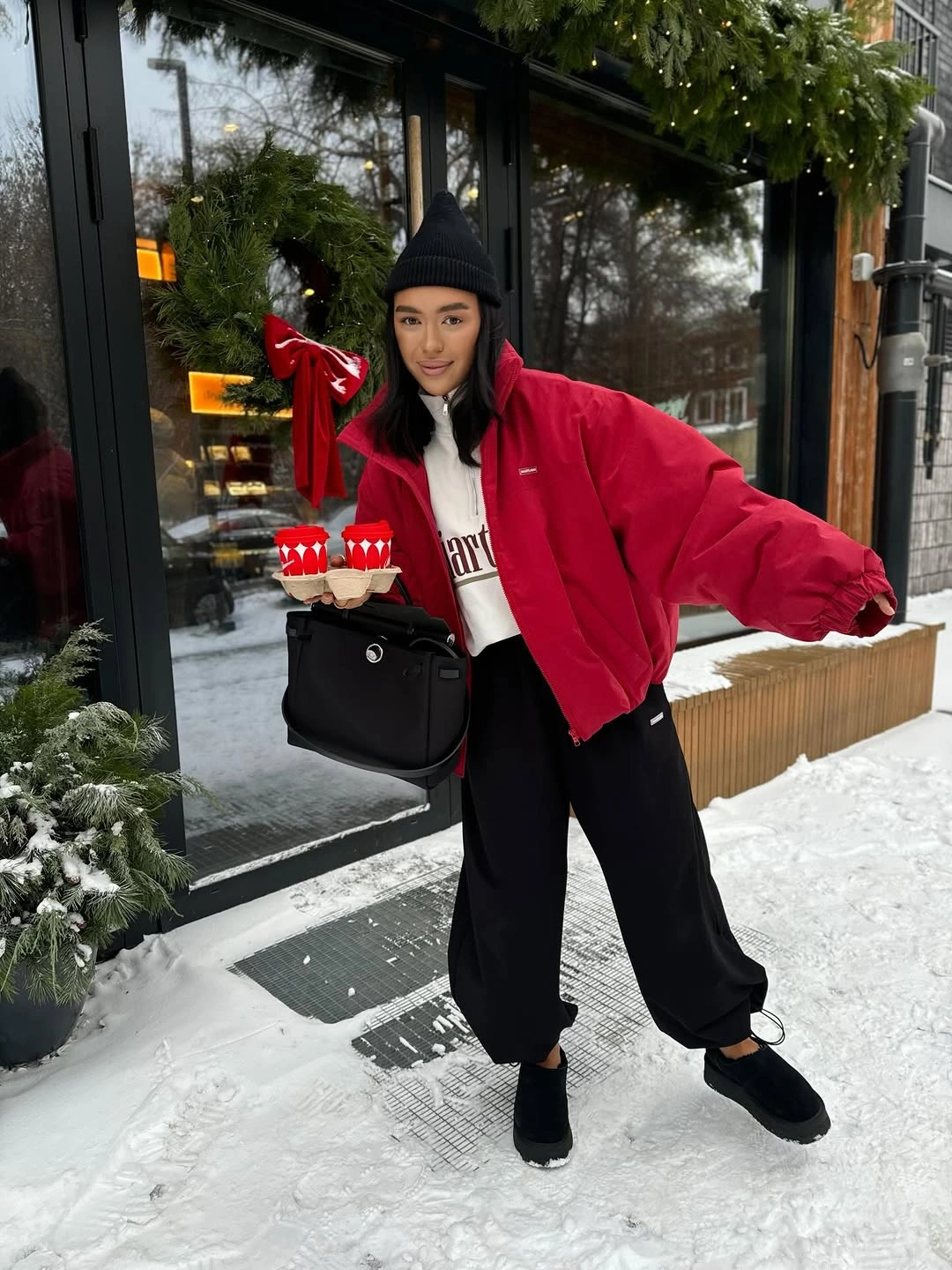Bright red oversized jacket over white sweatshirt with loose black trousers and black accessories