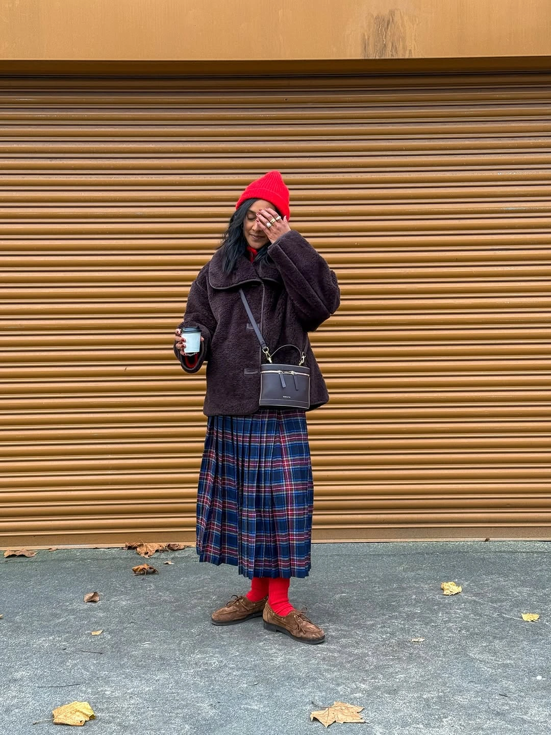 Dark textured jacket with blue plaid midi skirt and red beanie