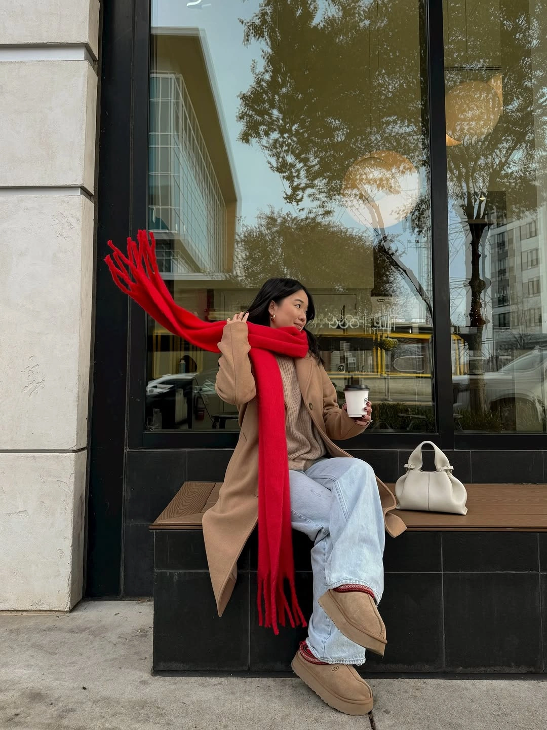 Camel coat with long red scarf, pale jeans, white bag, and tan boots