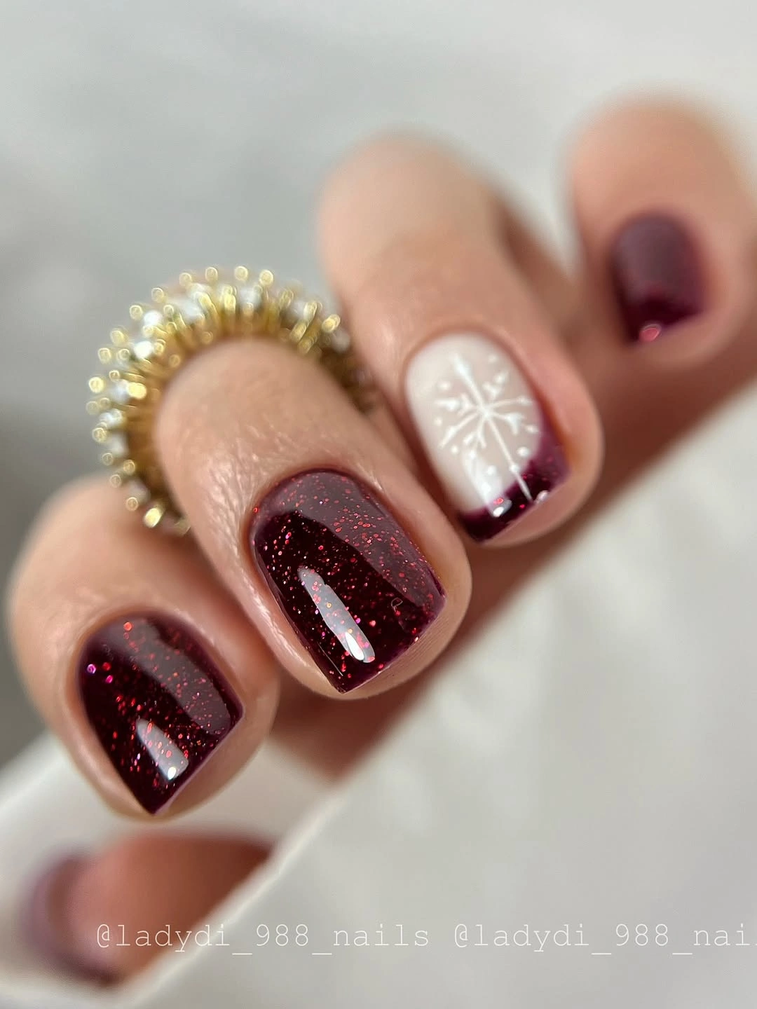 Short burgundy glitter nails with pale snowflake accent