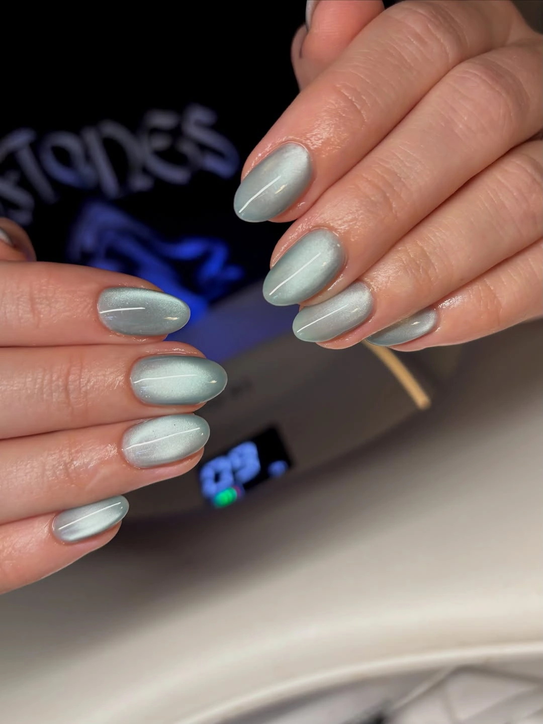 Short sage gray oval nails with diagonal reflective sheen