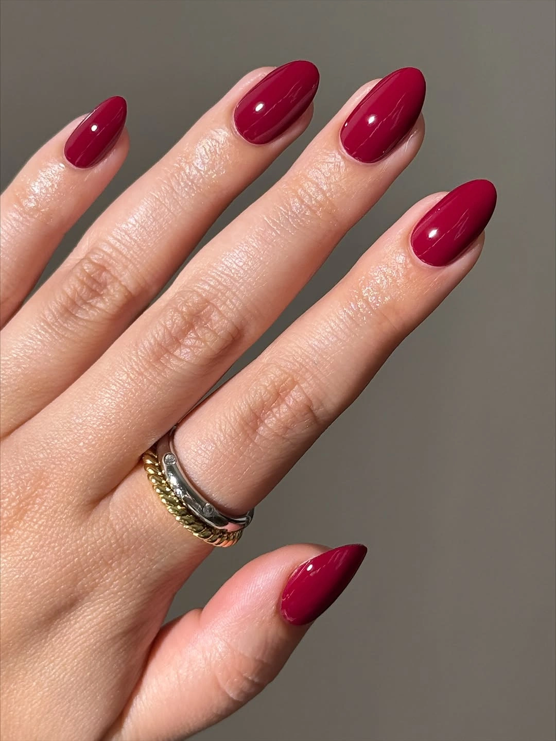 Glossy deep berry red almond nails on hand
